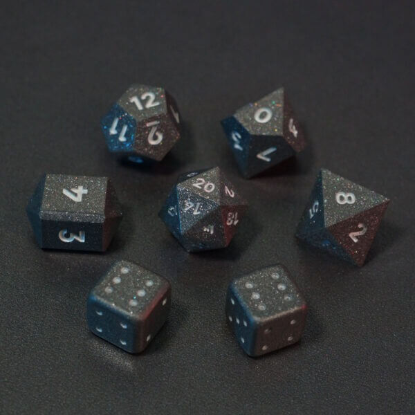 Set of 7 lit Hematite Grey dice with a rainbow of colors across all faces. Set Includes: 1 D20, 1 D12, 1 D10, 1 D8, 2 Pipped D6, 1 D4. Hematite Grey colorway is a fully opaque medium tone silver resin packed with rainbow glitter of various sizes. The numbers or symbols are painted pale white.