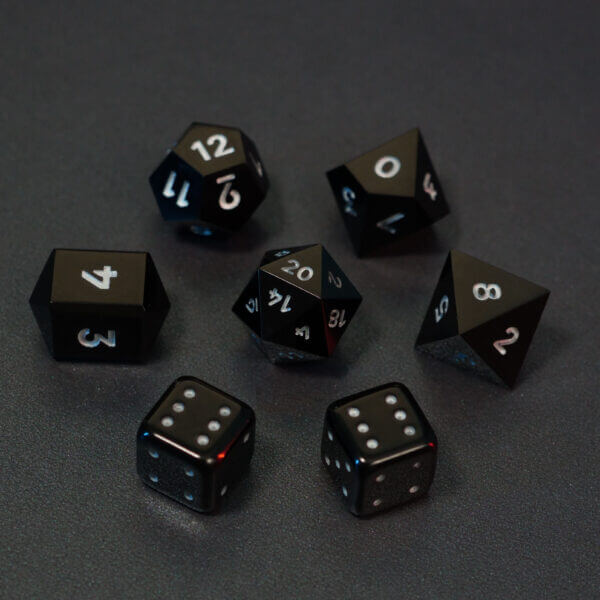 Set of 7 lit Onyx Black dice with a rainbow of colors across all faces. Set Includes: 1 D20, 1 D12, 1 D10, 1 D8, 2 Pipped D6, 1 D4. Onyx Black colorway is a fully opaque black resin with no glitter. The numbers or symbols are painted pale white.