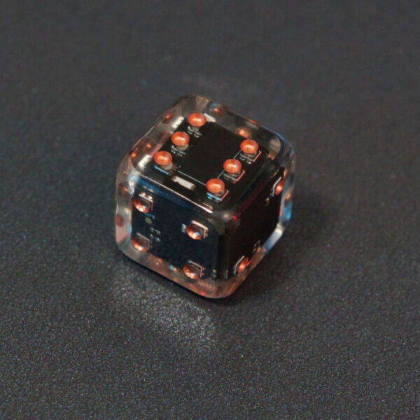 Collage of 7 lit Clear Pipped D6 with a rainbow of colors across each face. Clear colorway is fully transparent resin allowing internal circuit board to be visible. The numbers or symbols are painted metallic copper.