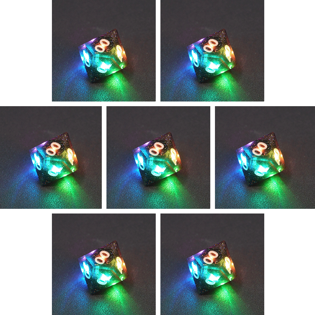 Collage of 7 lit Midnight Galaxy D00 with a rainbow of colors across each face. Midnight Galaxy colorway is a mostly translucent dark smoke black resin base packed with rainbow glitter of various sizes. The numbers or symbols are painted pearl white.