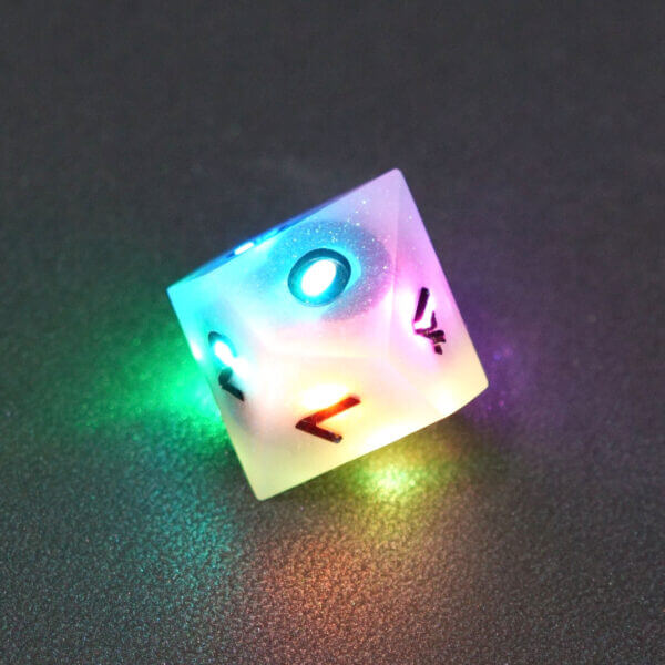 Collage of 7 lit Aurora Sky D10 with a rainbow of colors across each face. Aurora Sky colorway is a mostly translucent white resin base packed with small blue and silver glitter throughout. The numbers or symbols are painted metallic black.