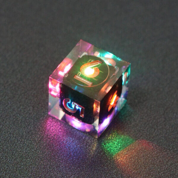 Collage of 7 lit Clear D6 with a rainbow of colors across each face. Clear colorway is fully transparent resin allowing internal circuit board to be visible. The numbers or symbols are painted metallic copper.