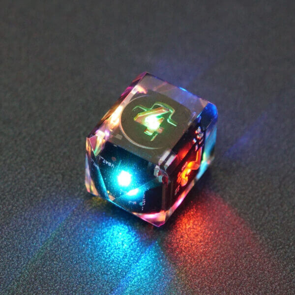 Collage of 7 lit Clear D4 in a crystal shape with a rainbow of colors across each face. Clear colorway is fully transparent resin allowing internal circuit board to be visible. The numbers or symbols are painted metallic copper.