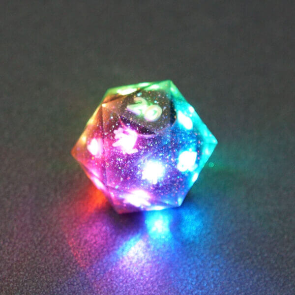 Collage of 7 lit Midnight Galaxy D20 with a rainbow of colors across each face. Midnight Galaxy colorway is a mostly translucent dark smoke black resin base packed with rainbow glitter of various sizes. The numbers or symbols are painted pearl white.
