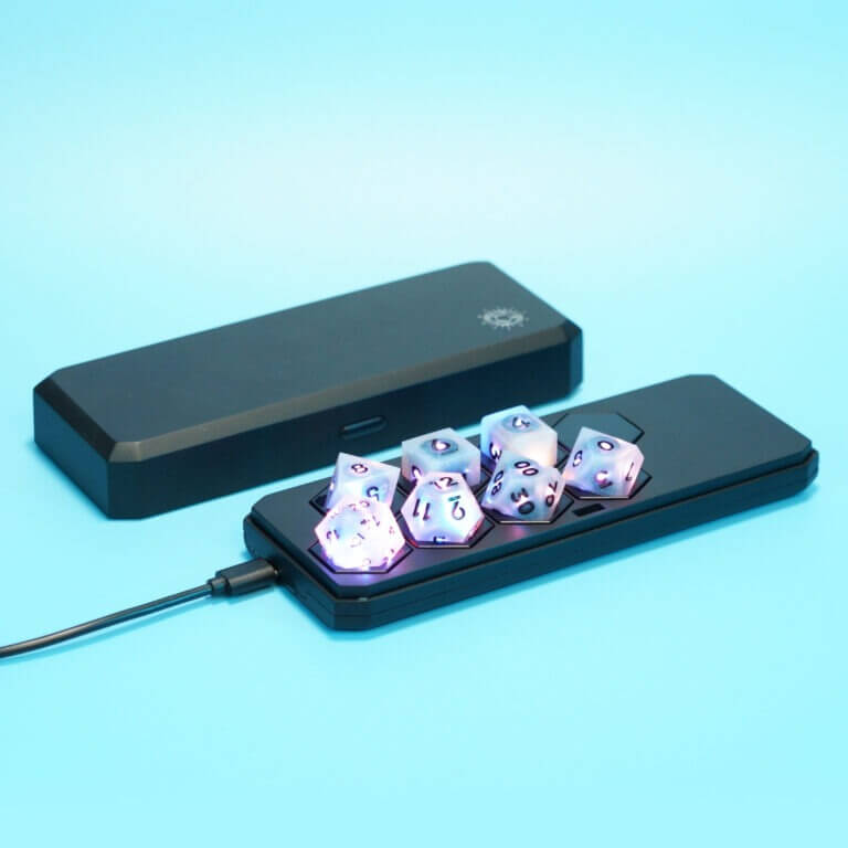 Set of 7 lit Aurora Sky dice with a rainbow of colors across all faces. Set Includes: 1 D20, 1 D12, 1 D00, 1 D10, 1 D8, 1 D6, 1 D4. Aurora Sky colorway is a mostly translucent white resin base packed with small blue and silver glitter throughout. The numbers or symbols are painted metallic black.