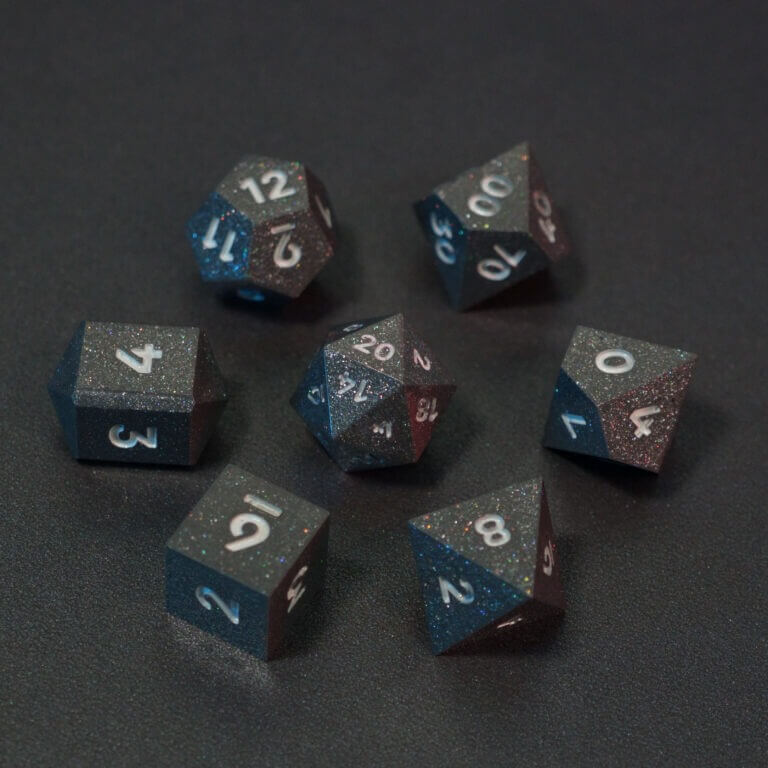 Set of 7 lit Hematite Grey dice with a rainbow of colors across all faces. Set Includes: 1 D20, 1 D12, 1 D00, 1 D10, 1 D8, 1 D6, 1 D4. Hematite Grey colorway is a fully opaque medium tone silver resin packed with rainbow glitter of various sizes. The numbers or symbols are painted pale white.