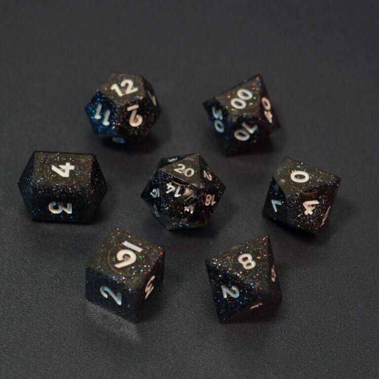 Set of 7 lit Midnight Galaxy dice with a rainbow of colors across all faces. Set Includes: 1 D20, 1 D12, 1 D00, 1 D10, 1 D8, 1 D6, 1 D4. Midnight Galaxy colorway is a mostly translucent dark smoke black resin base packed with rainbow glitter of various sizes. The numbers or symbols are painted pearl white.