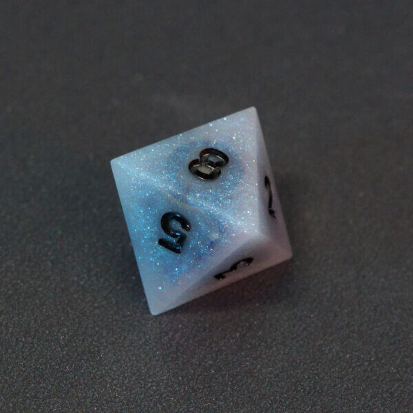 Collage of 7 lit Aurora Sky D8 with a rainbow of colors across each face. Aurora Sky colorway is a mostly translucent white resin base packed with small blue and silver glitter throughout. The numbers or symbols are painted metallic black.