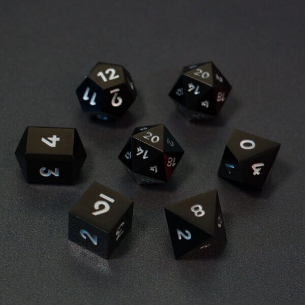 Set of 7 lit Onyx Black dice with a rainbow of colors across all faces. Set Includes: 2 D20, 1 D12, 1 D10, 1 D8, 1 D6, 1 D4. Onyx Black colorway is a fully opaque black resin with no glitter. The numbers or symbols are painted pale white.