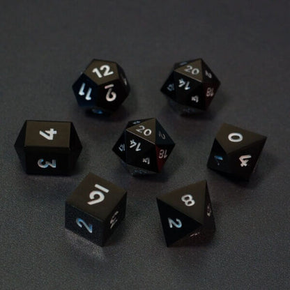 Set of 7 lit Onyx Black dice with a rainbow of colors across all faces. Set Includes: 2 D20, 1 D12, 1 D10, 1 D8, 1 D6, 1 D4. Onyx Black colorway is a fully opaque black resin with no glitter. The numbers or symbols are painted pale white.