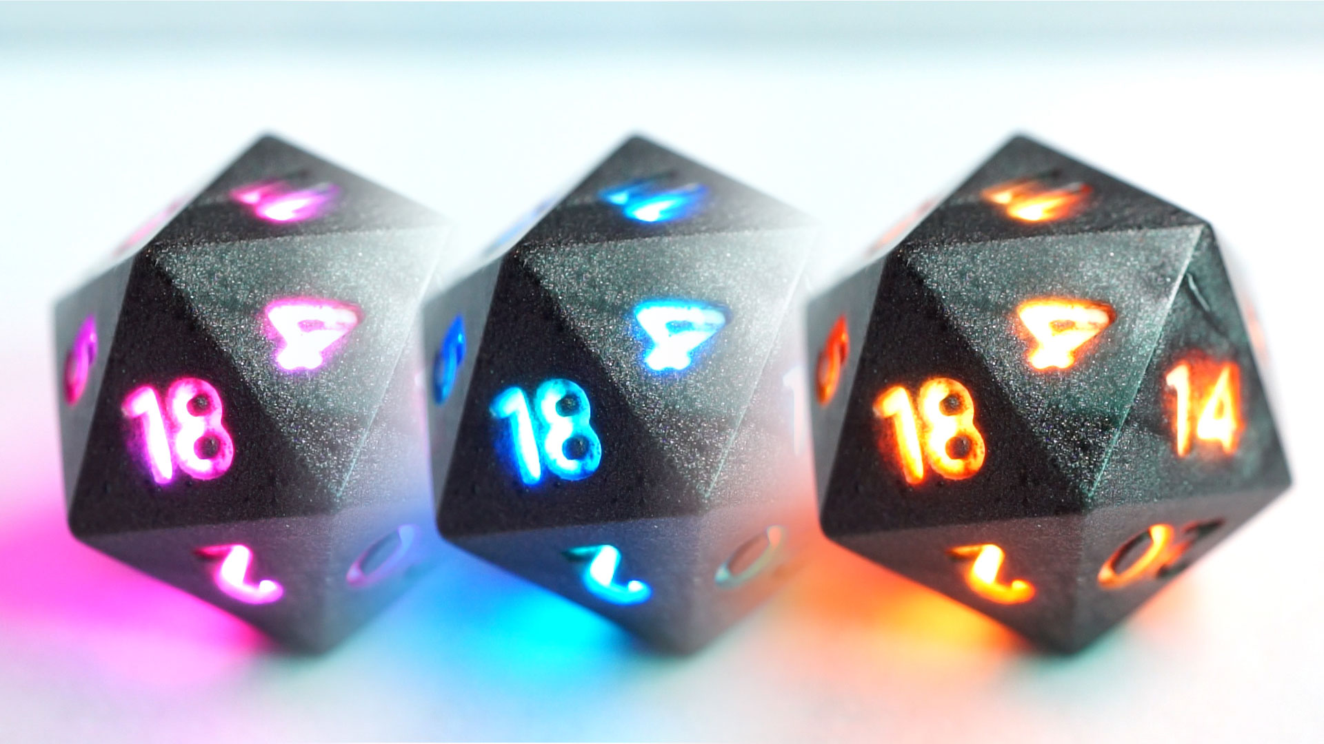 3 gray D20s with different colored lit up numbers.