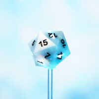 Partially white lit Aurora Sky D20 on a blue background. Aurora Sky colorway is a mostly translucent white resin base packed with small blue and silver glitter throughout. The numbers or symbols are painted metallic black.