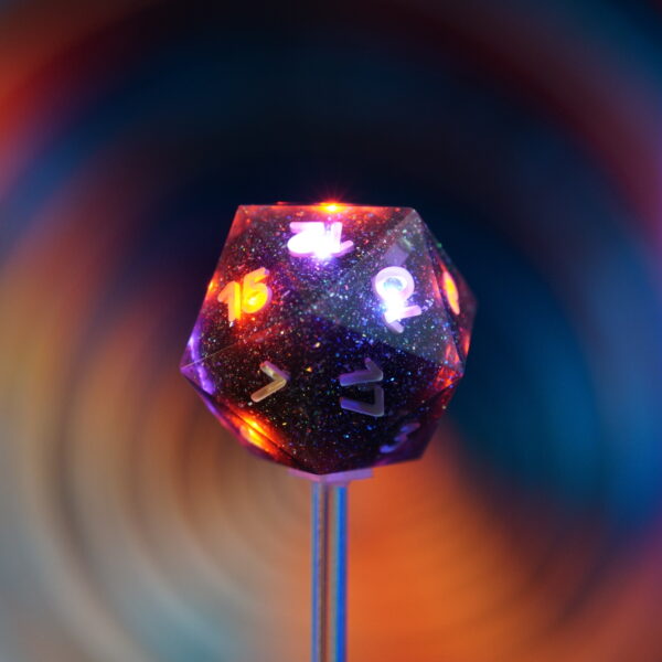 Partially lit Midnight Galaxy D20 in front of a colored background.