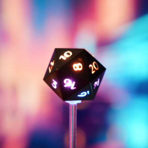Lit Onyx Black D20 with a rainbow of colors across each face, positioned in front of a rainbow background.