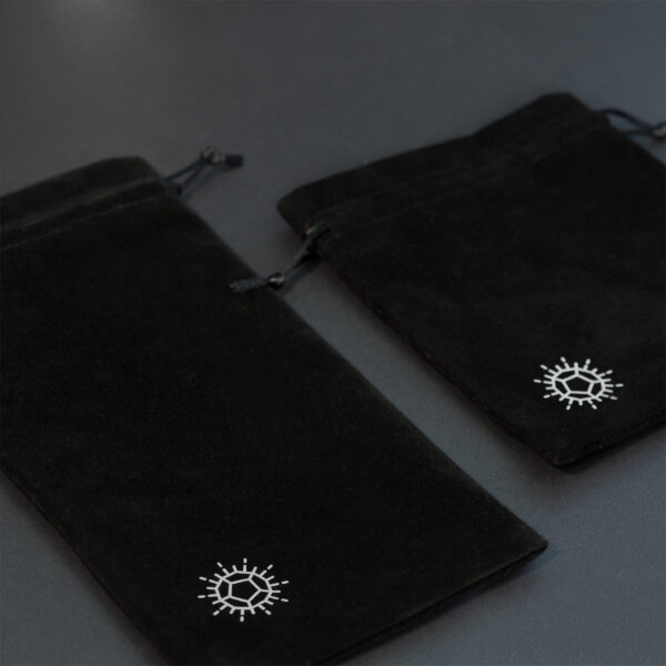 Two different sized black velvet drawstring bags with Pixels D12 shaped starburst logo in one corner.