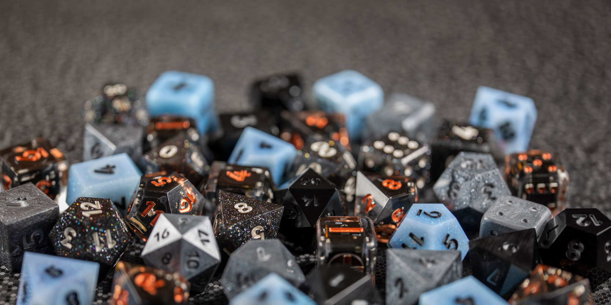 Photograph of a large pile of Pixels Dice in various colorways. All lights are off, making them look like regular dice.