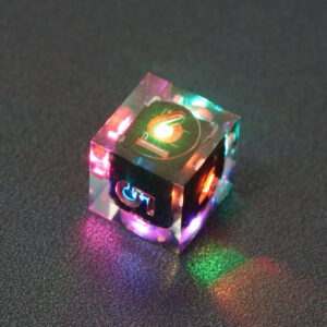 Lit Clear D6 with a rainbow of colors across each face. Clear colorway is fully transparent resin allowing internal circuit board to be visible. The numbers or symbols are painted metallic copper.