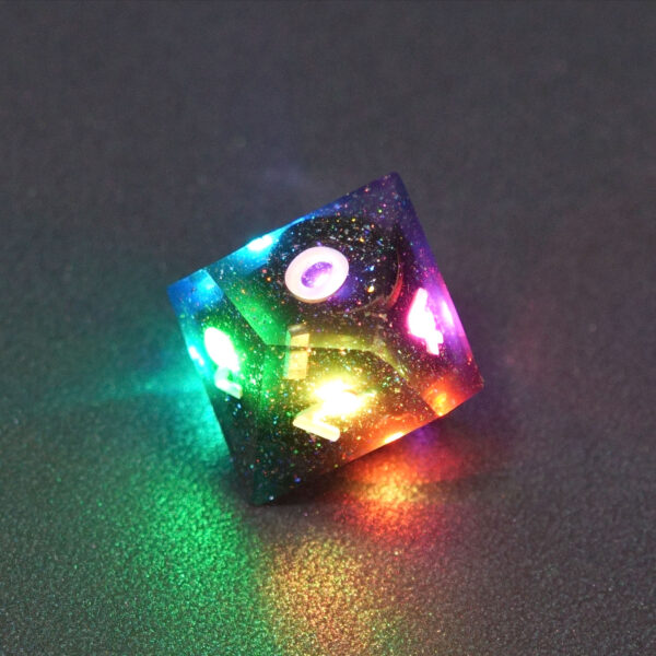 Lit Midnight Galaxy D10 with a rainbow of colors across each face. Midnight Galaxy colorway is a mostly translucent dark smoke black resin base packed with rainbow glitter of various sizes. The numbers or symbols are painted pearl white.