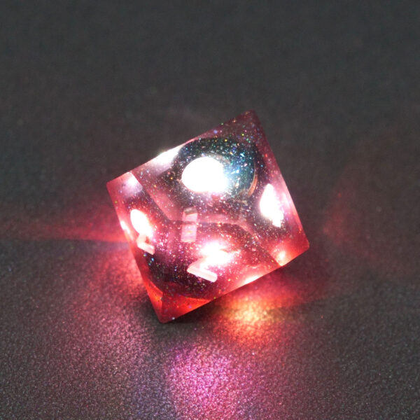 Lit Midnight Galaxy D10 with red colors across each face. Midnight Galaxy colorway is a mostly translucent dark smoke black resin base packed with rainbow glitter of various sizes. The numbers or symbols are painted pearl white.