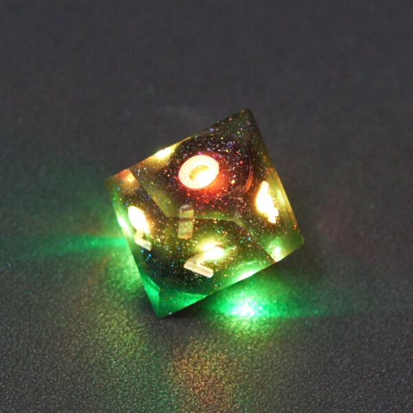 Lit Midnight Galaxy D12 with green and yellow colors across each face. Midnight Galaxy colorway is a mostly translucent dark smoke black resin base packed with rainbow glitter of various sizes. The numbers or symbols are painted pearl white.