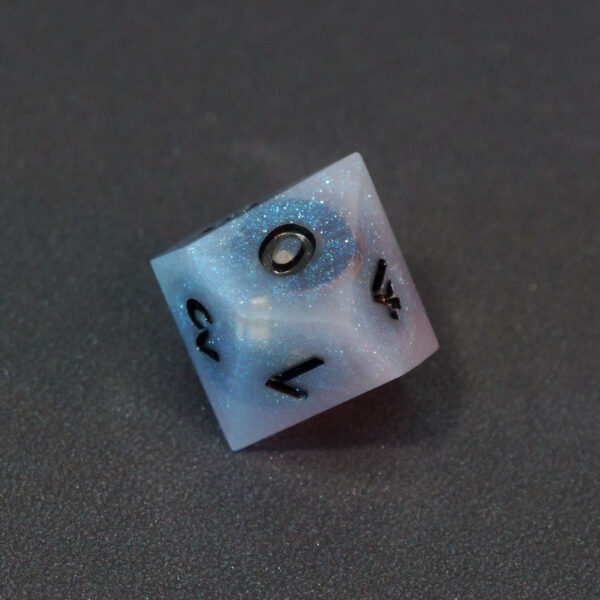 Unlit Aurora Sky D10. Aurora Sky colorway is a mostly translucent white resin base packed with small blue and silver glitter throughout. The numbers or symbols are painted metallic black.