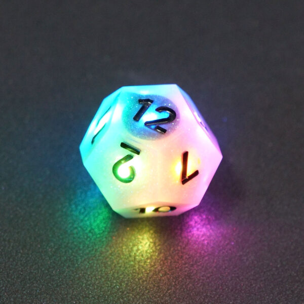 Lit Aurora Sky D12 with rainbow lights across each face. Aurora Sky colorway is a mostly translucent white resin base packed with small blue and silver glitter throughout. The numbers or symbols are painted metallic black.