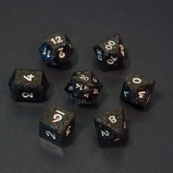 Set of 7 unlit Midnight Galaxy dice. Set Includes: 1 D20, 1 D12, 1 D00, 1 D10, 1 D8, 1 D6, 1 D4. Midnight Galaxy colorway is a mostly translucent dark smoke black resin base packed with rainbow glitter of various sizes. The numbers or symbols are painted pearl white.