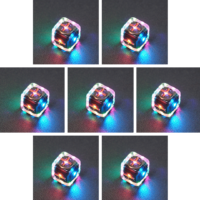 Collage of 7 lit Clear Fudge D6 with a rainbow of colors across each face. Clear colorway is fully transparent resin allowing internal circuit board to be visible. The numbers or symbols are painted metallic copper.