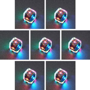 Collage of 7 lit Clear Fudge D6 with a rainbow of colors across each face. Clear colorway is fully transparent resin allowing internal circuit board to be visible. The numbers or symbols are painted metallic copper.