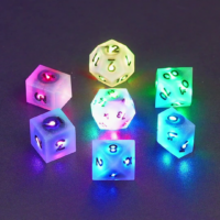 Set of 7 lit Aurora Sky dice with a rainbow of colors across all faces. Set Includes: 1 D20, 1 D12, 1 D00, 1 D10, 1 D8, 1 D6, 1 D4. Aurora Sky colorway is a mostly translucent white resin base packed with small blue and silver glitter throughout. The numbers or symbols are painted metallic black.