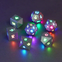 Set of 7 lit Hematite Grey dice with a rainbow of colors across all faces. Set Includes: 2 D20, 1 D12, 1 D10, 1 D8, 1 D6, 1 D4. Hematite Grey colorway is a fully opaque medium tone silver resin packed with rainbow glitter of various sizes. The numbers or symbols are painted pale white.