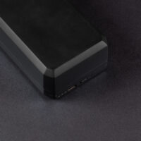 Large Charging Case - side. Short side of a long rectangular shaped box. Three unlit LED circles, a USB Type-C port, and button are in place on the bottom of the case.