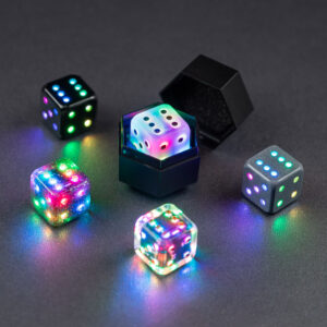 Photograph of five Pipped D6 Pixels Dice in colorways Onyx Black, Midnight Galaxy, Aurora Sky, Clear, and Hematite Grey. All dice are lit a rainbow of colors with one color per pip.